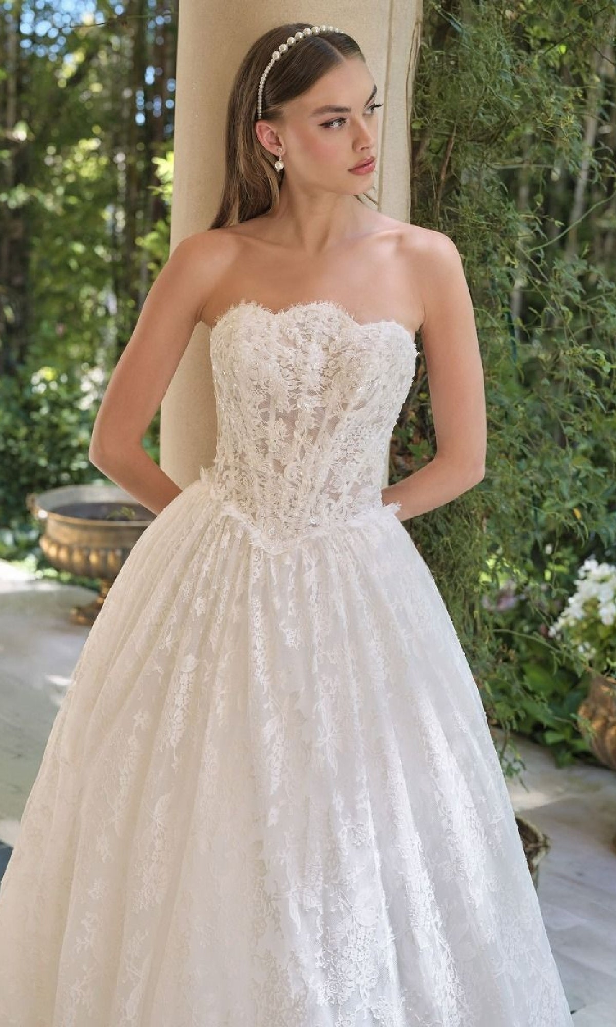Woman wearing a strapless lace wedding dress in an outdoor setting